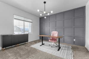 Office featuring a decorative wall, carpet, baseboards, and a chandelier