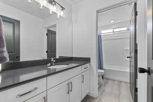 Full bathroom with toilet, vanity, wood finished floors, and shower / tub combo with curtain