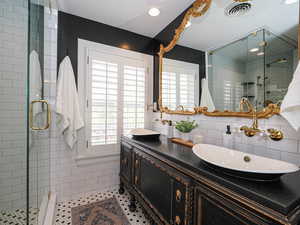 Full bathroom featuring tile walls, a shower stall, double vanity, recessed lighting, and tile patterned flooring