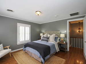 Bedroom featuring wood finished floors, ornamental molding, and baseboards