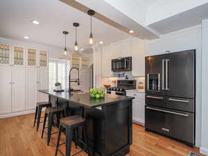 Kitchen with high quality fridge, gas stove, dark countertops, crown molding, and a sink
