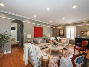 Living area featuring arched walkways, wood finished floors, ornamental molding, baseboards, and recessed lighting