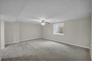 Unfurnished room with a ceiling fan, carpet flooring, baseboards, and a textured ceiling