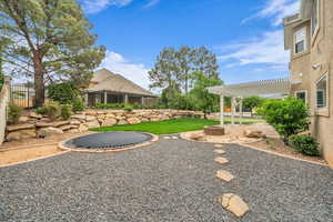 Fenced backyard with a trampoline, outdoor fire pit, and a patio area