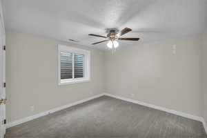 Empty room with a ceiling fan, a textured ceiling, carpet flooring, and baseboards