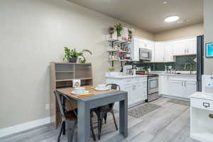 Kitchen with appliances with stainless steel finishes, light countertops, open shelves, and light wood-style floors