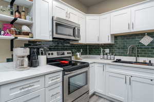Kitchen featuring stainless steel appliances, a sink, and white cabinets