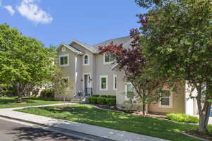 Traditional-style house with stucco siding and a front yard