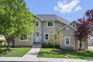 View of front facade featuring stucco siding and a front yard