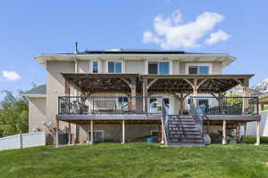 Rear view of property featuring stucco siding, roof mounted solar panels, and stairs