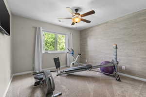 Workout area with ceiling fan, an accent wall, baseboards, and carpet floors