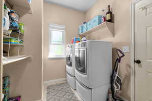 Washroom with separate washer and dryer, baseboards, and light tile patterned flooring