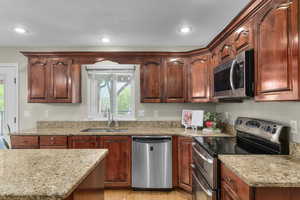 Kitchen with stainless steel appliances, a sink, light stone countertops, light wood-style flooring, and recessed lighting