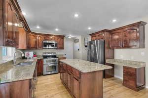 Kitchen featuring appliances with stainless steel finishes, a sink, light wood-style flooring, recessed lighting, and a center island