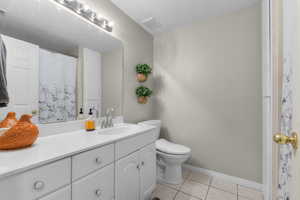 Full bath with tile patterned flooring, baseboards, toilet, and vanity