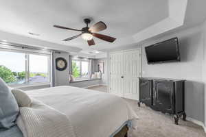 Bedroom featuring light colored carpet, baseboards, a closet, ceiling fan, and a tray ceiling