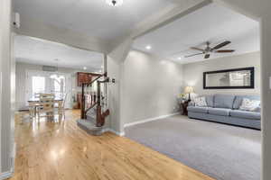 Living room with wood finished floors, baseboards, a ceiling fan, stairs, and recessed lighting