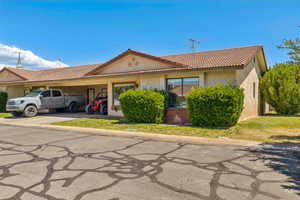 View of front of home featuring an attached carport, stucco siding, a tiled roof, and driveway