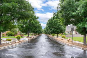 View of asphalt street featuring sidewalks, curbs, and traffic signs