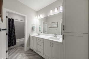 Bathroom with double vanity and shower / tub combo with curtain