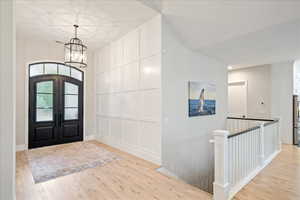 Entrance foyer featuring a chandelier, light wood-style floors, french doors, and baseboards