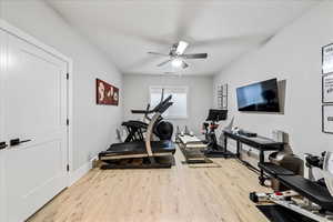 Workout room featuring wood finished floors, a ceiling fan, and baseboards