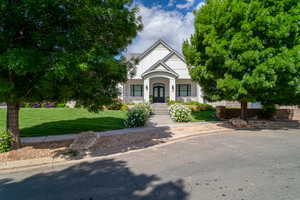 Tudor house with covered porch, a front yard, french doors, and stucco siding