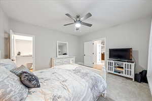 Carpeted bedroom with ceiling fan and ensuite bathroom