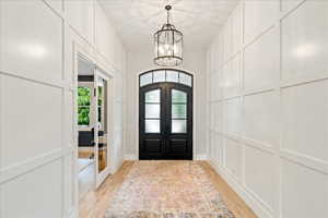 Entryway featuring french doors, light wood-style flooring, and a chandelier