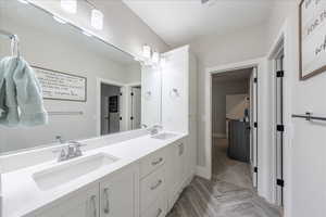 Full bathroom with double vanity and baseboards