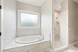 Full bathroom with tiled shower, a bath, marble finish floors, and baseboards
