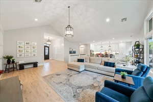 Living room with a chandelier, light wood-style flooring, high vaulted ceiling, recessed lighting, and baseboards