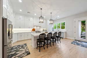 Kitchen featuring appliances with stainless steel finishes, light countertops, recessed lighting, light wood-style flooring, and tasteful backsplash