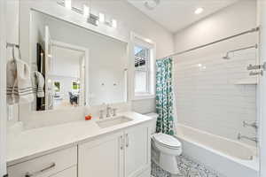 Bathroom with toilet, shower / bathtub combination with curtain, vanity, and tile patterned floors