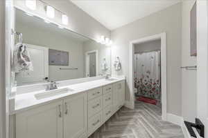 Full bathroom with baseboards, double vanity, toilet, and curtained shower