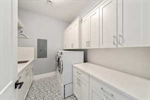 Laundry room with electric panel, cabinet space, baseboards, independent washer and dryer, and light tile patterned flooring