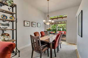 Dining area featuring baseboards, a chandelier, light wood-style flooring, and a towering ceiling