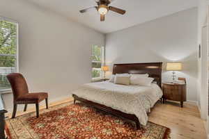 Bedroom with light wood-style floors, baseboards, and a ceiling fan