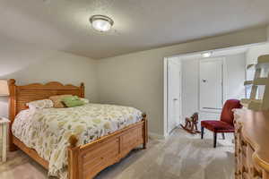 Bedroom with light colored carpet, baseboards, and a textured ceiling
