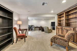 Living area with light carpet, recessed lighting, and a desk
