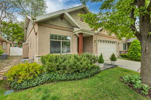 View of front of property featuring stucco siding, stone siding, a garage, and driveway