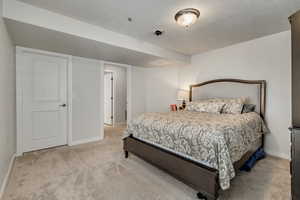 Carpeted bedroom featuring baseboards and a textured ceiling