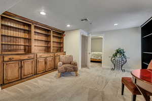 Living area with light carpet, baseboards, and recessed lighting