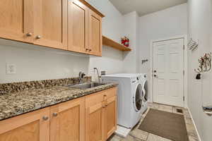 Washroom featuring cabinet space, washer and clothes dryer, and baseboards