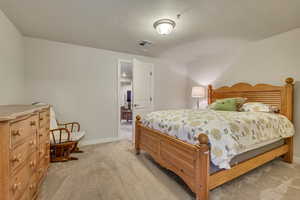 Carpeted bedroom featuring a textured ceiling and baseboards
