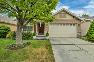 View of front of house featuring a garage, stone siding, driveway, a front yard, and stucco siding