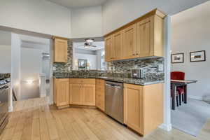 Kitchen with dishwasher, light brown cabinets, a sink, and light wood-style flooring