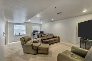 Living room featuring carpet, baseboards, recessed lighting, and a textured ceiling