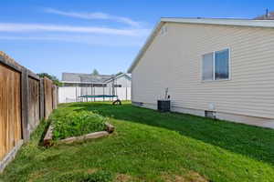 View of home's exterior with a trampoline, central AC unit, and a garden