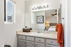 Ensuite bathroom featuring healthy amount of natural light, vanity, and a ceiling fan
